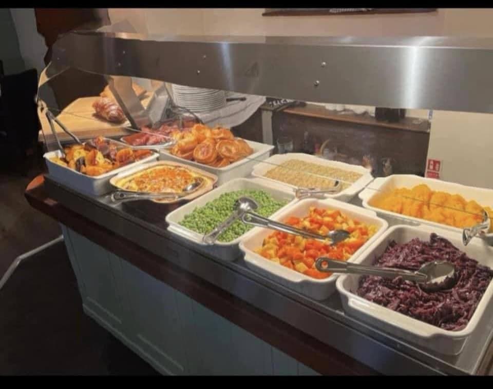 The Sunday Carvery counter -- Yorkshire puddings, roast potatoes, peas, seasonal vegetables, red cabbage and carved meat under a hot pass.