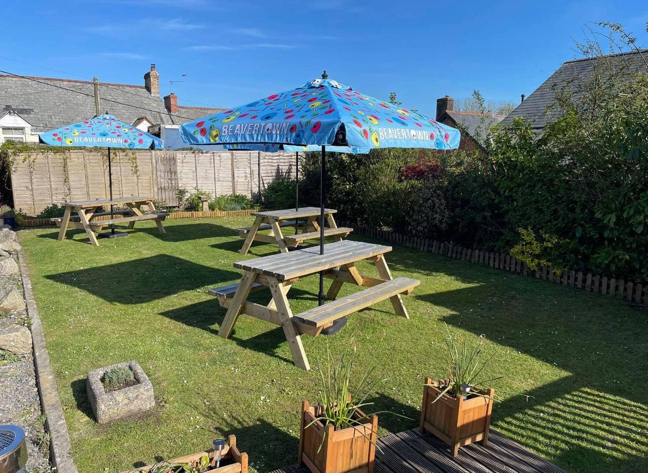 The Olde Market Inn beer garden on a sunny day -- picnic benches on the lawn under a Beavertown umbrella.